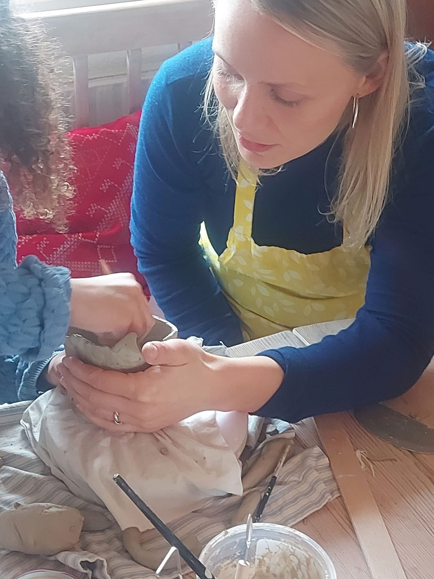 Kia guider hænder i leret ved langbordet